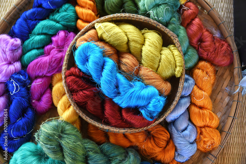 Tie of colorful and shiny beautiful silk yarn dyed placed in a pile of round bamboo baskets. Prepared for use as a raw material for weaving silk.