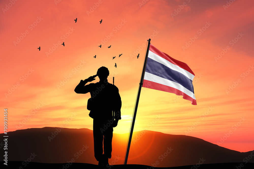 Silhouette of a soldier with the Thailand flag stands against the background of a sunset or sunrise. Concept of national holidays. Commemoration Day.