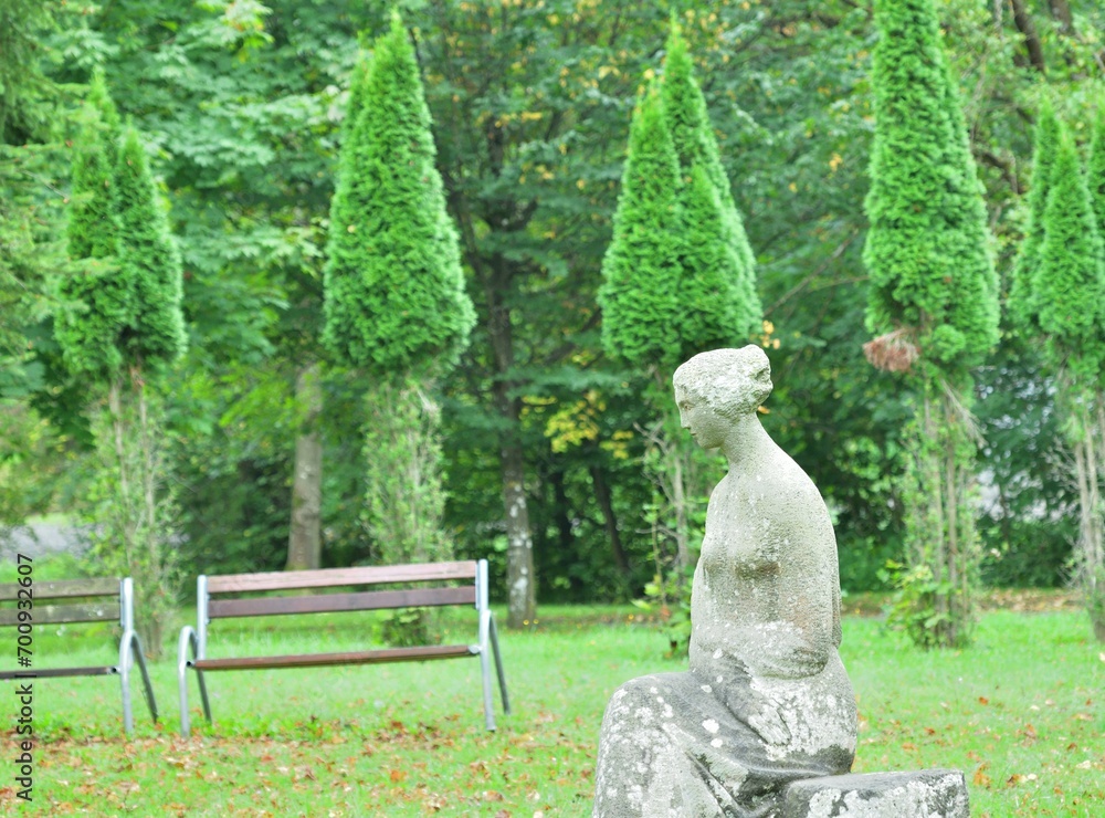 Decorative stone sculpture built in a garden park with bench and trees