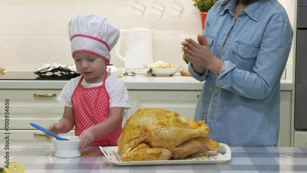 mother and child in chef uniform cooking roasted stuffed turkey in kitchen, preparing thanksgiving or christmas holiday dinner mother and child in chef uniform cooking roasted stuffed turkey in kitchen, preparing thanksgiving or christmas holiday dinner