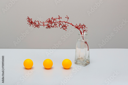 Still life with a red branch vase and balls on a gray background