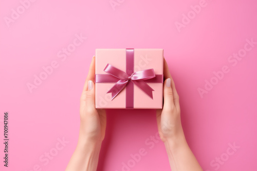 Woman hand holding a gift box on pink background. Valentine's day background. Top view, copy space. © Emre Akkoyun