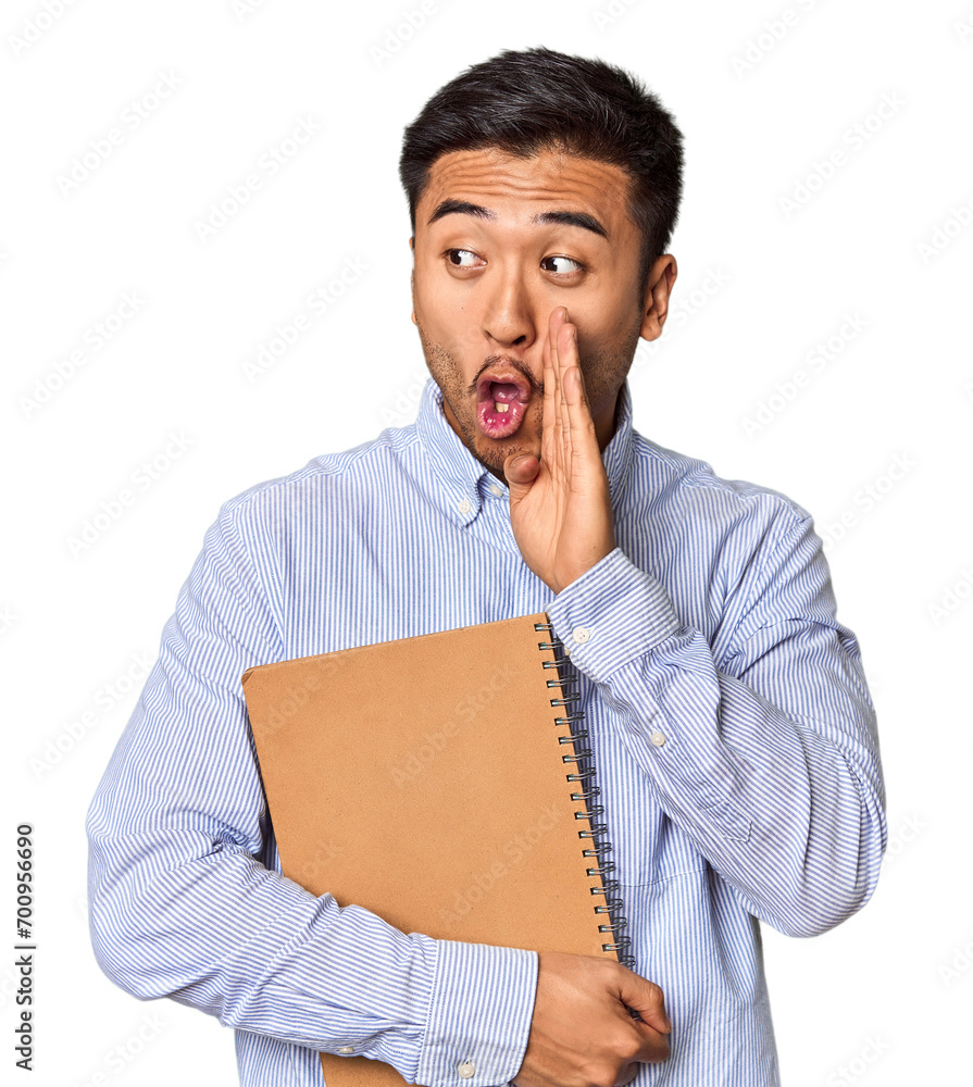 Chinese student with a notebook in studio is saying a secret hot braking news and looking aside Chinese student with a notebook in studio is saying a secret hot braking news and looking aside