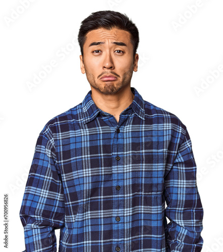 Young Chinese man in studio background sad, serious face, feeling miserable and displeased.