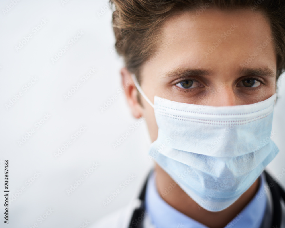 Man, portrait and doctor with face mask for safety, protection or health on mockup space. Closeup of male person, surgeon or medical professional for safe healthcare on a white studio background