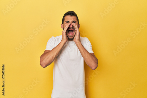 Young Hispanic man on yellow background shouting excited to front.