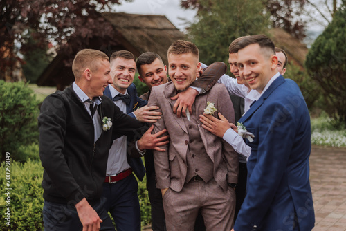Cheerful, young, energetic witnesses of the groom next to the groom. Friends congratulate the groom. Groom and his funny friends having fun on the wedding day of the newlyweds.