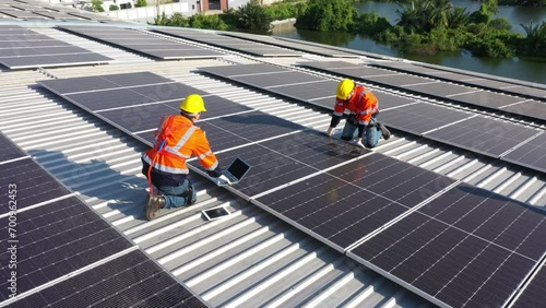Engineering technician is professional trained in skills and techniques installing solar photovoltaic panels system on power industrial factory roof, Engineering concepts to good environment. photo