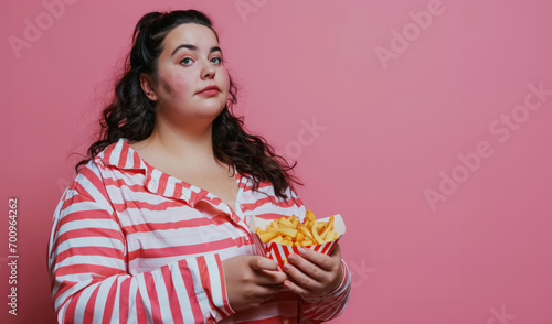 Very fat girl on pink background with fast food in her hands, the harm of food