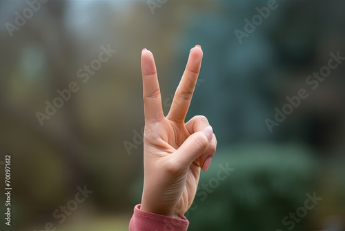 A hand making a victory gesture with two fingers pointed upwards. © jambulart