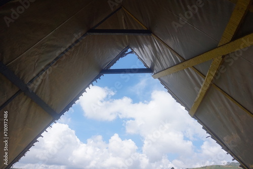 Tent with blue sky and white clouds in the mountains. View from inside.