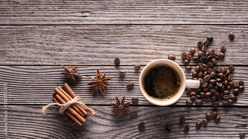 top view glass cup with espresso, coffee beans, star anise and cinnamon sticks on a gray wooden background with empty space above view photo
