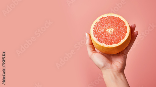 Hand holding sliced grapefruit isolated on pastel background