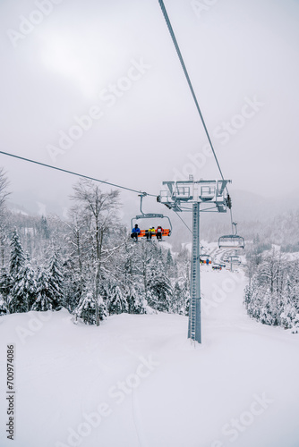 Chairlift with skiers ascends a snowy slope in the Kolasin 1600 resort. Montenegro