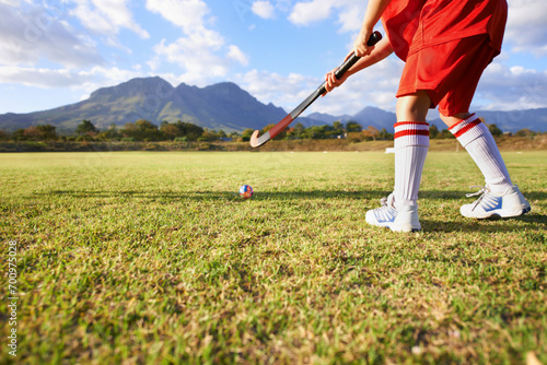 Person, green grass and playing hockey for game, outdoor match or sports in nature for practice. Closeup of child, kid or player enjoying competition with ball on field for fitness training outside