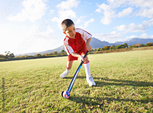 Fotografie Child, ball and playing hockey on green grass for game, sports or outdoor practice match