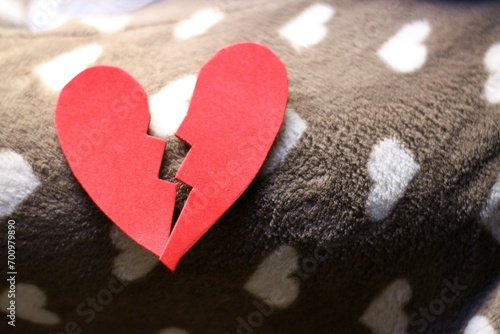 corazon rojo roto sobre una base de corazones blancos.