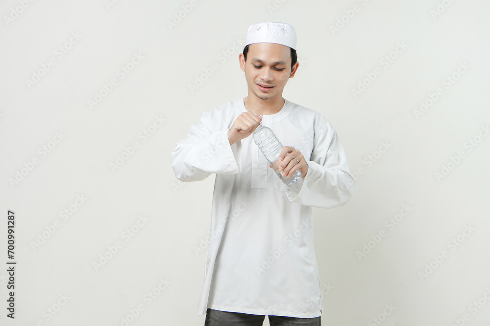 asian muslim man opening water bottle. People religious Islam lifestyle concept. celebration Ramadan and ied Mubarak. on isolated background. asian muslim man opening water bottle. People religious Islam lifestyle concept. celebration Ramadan and ied Mubarak. on isolated background.