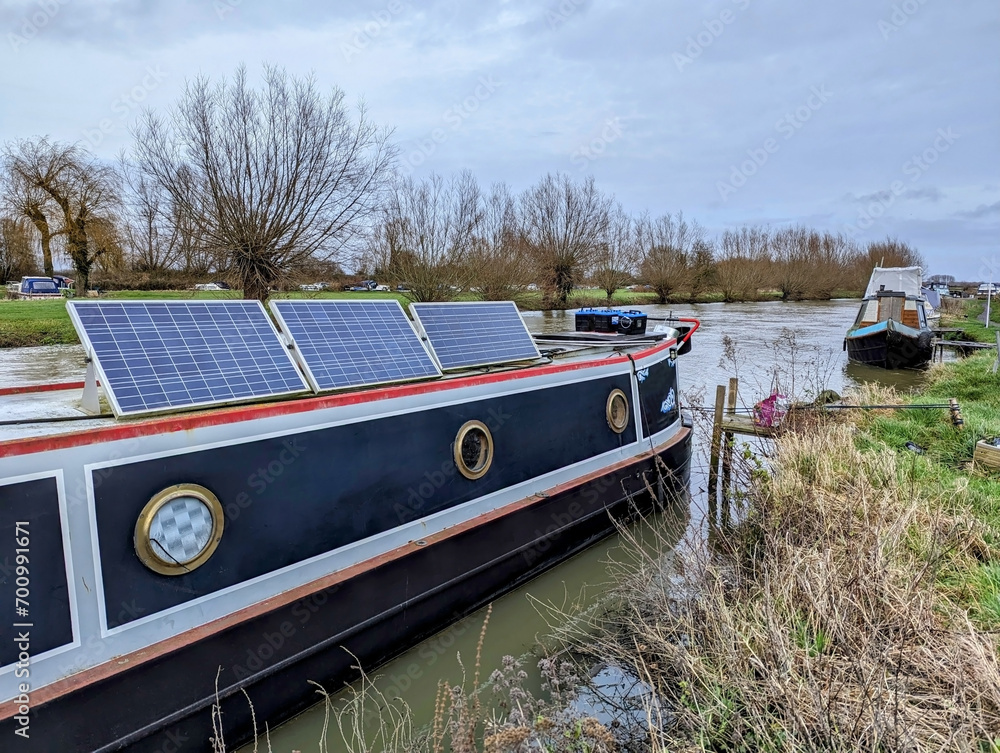 Solar panels and car batteries on the roof of a barge on a river. Renewable power solution for canal narrow boats. Solar panels and car batteries on the roof of a barge on a river. Renewable power solution for canal narrow boats.