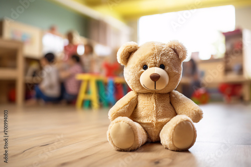 Teddy bear with blurry room with children iin children day care center, kindergarten or preschool´in background photo