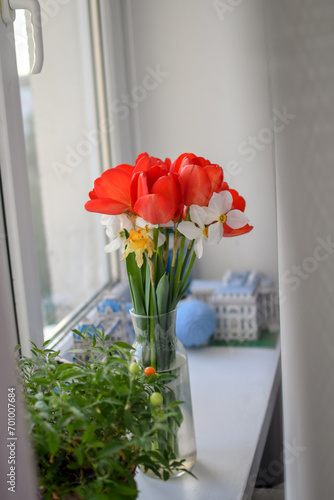 A bouquet of red tulips and white daffodils on the windowsill. Selective focus