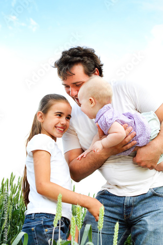 Happy father with daughters in green field