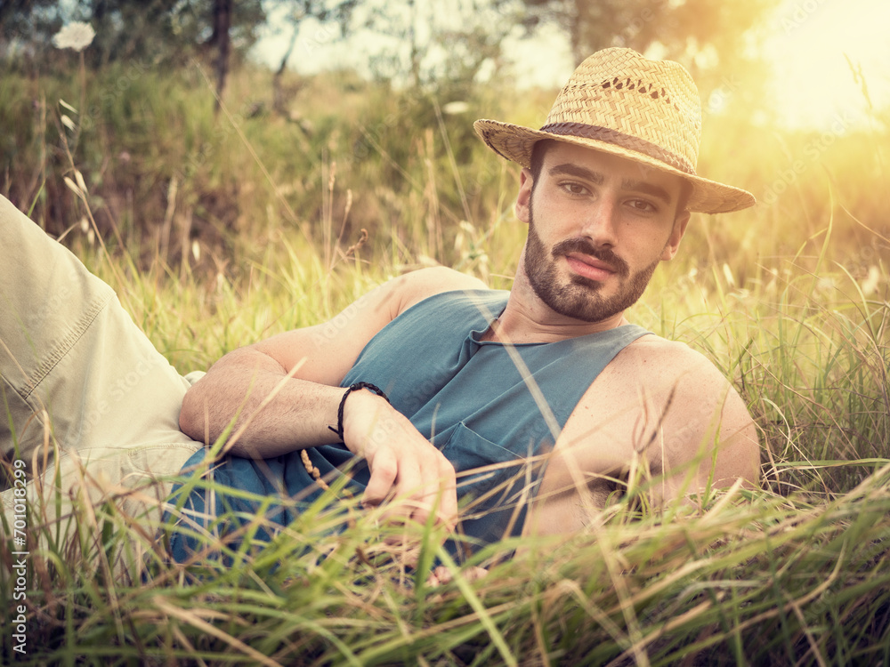 Male model relaxing, laying in a field