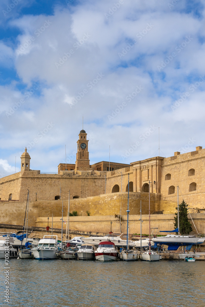 many boats in the Grand Harbor of Valletta with the fortress of Birgu in the background