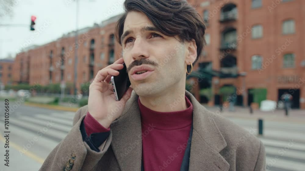 Young handsome businessman standing on the street and having phone conversation on autumn day in the city. Chest-up shot Young handsome businessman standing on the street and having phone conversation on autumn day in the city. Chest-up shot