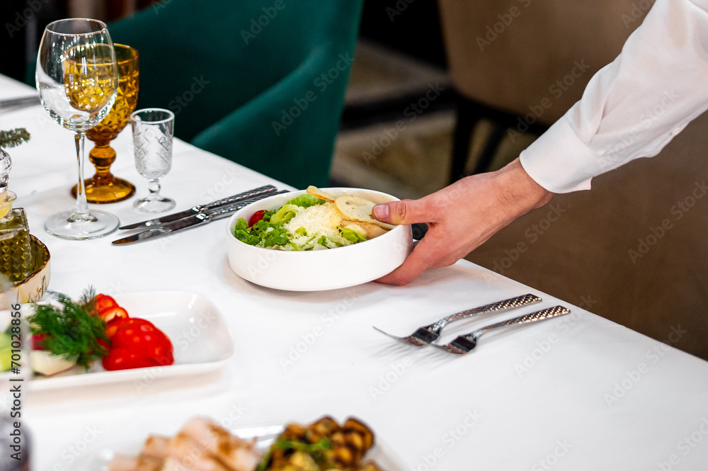 Men's waiter hands hold a Caesar salad Men's waiter hands hold a Caesar salad