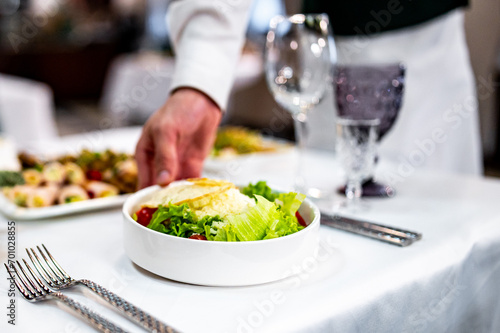 Men s waiter hands hold a Caesar salad 