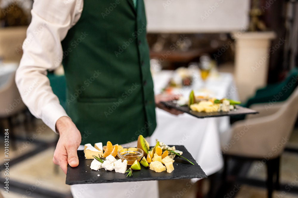 hand of a waiter hold plate with cheese food in restaurant