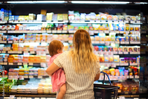 Фотография Cheerful mother and baby spending time in shopping in supermarket