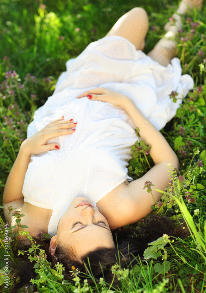 Fototapeta premium Beautiful pregnant woman relaxing on grass