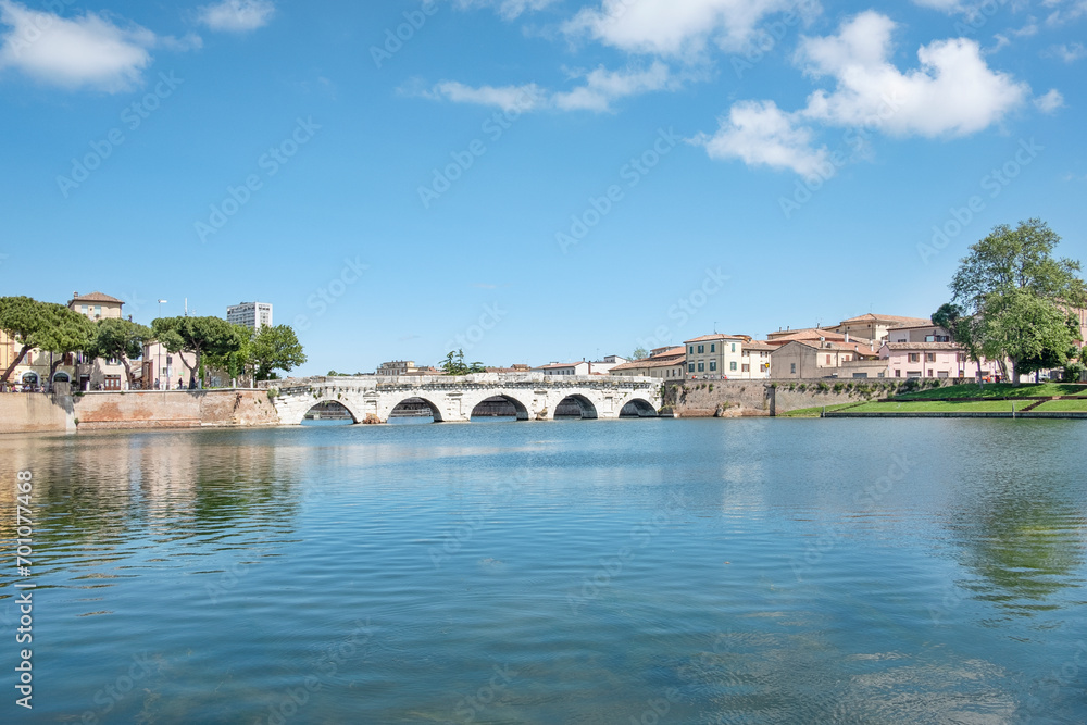 Beautiful day in the small Italian town near the canal end by the historic bridge known as The Tiberius Bridge, an iconic symbol of Roman engineering dating back to the first century AD, Rimini, Italy