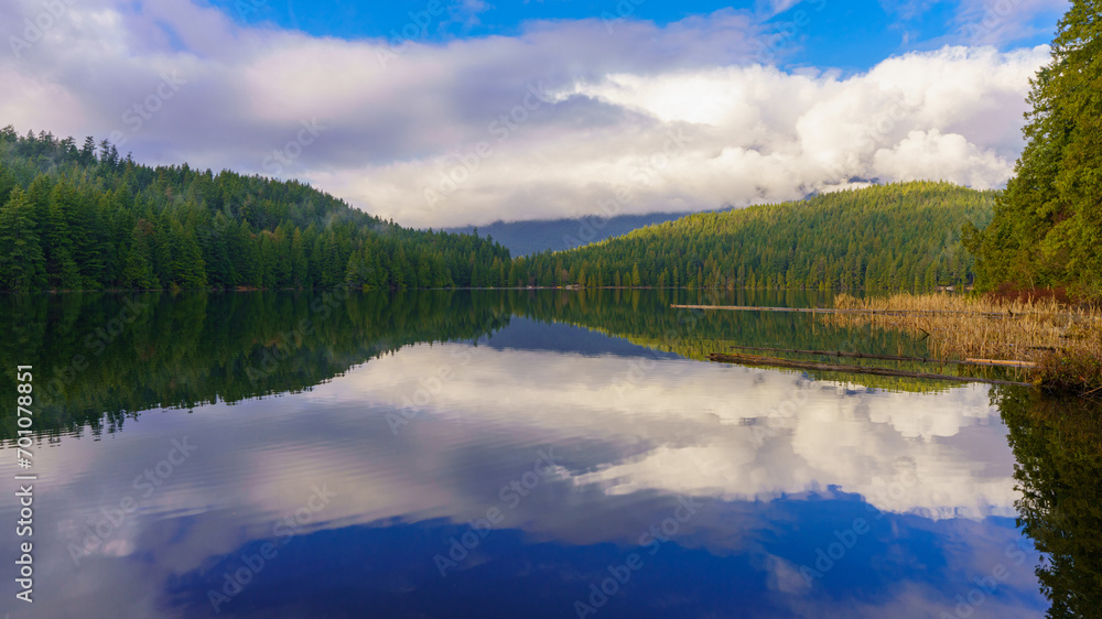 Clouds reflected in Sasamat Lake, BC, with mist rising from forest, as viewed from Sasamat Loop forest trail.