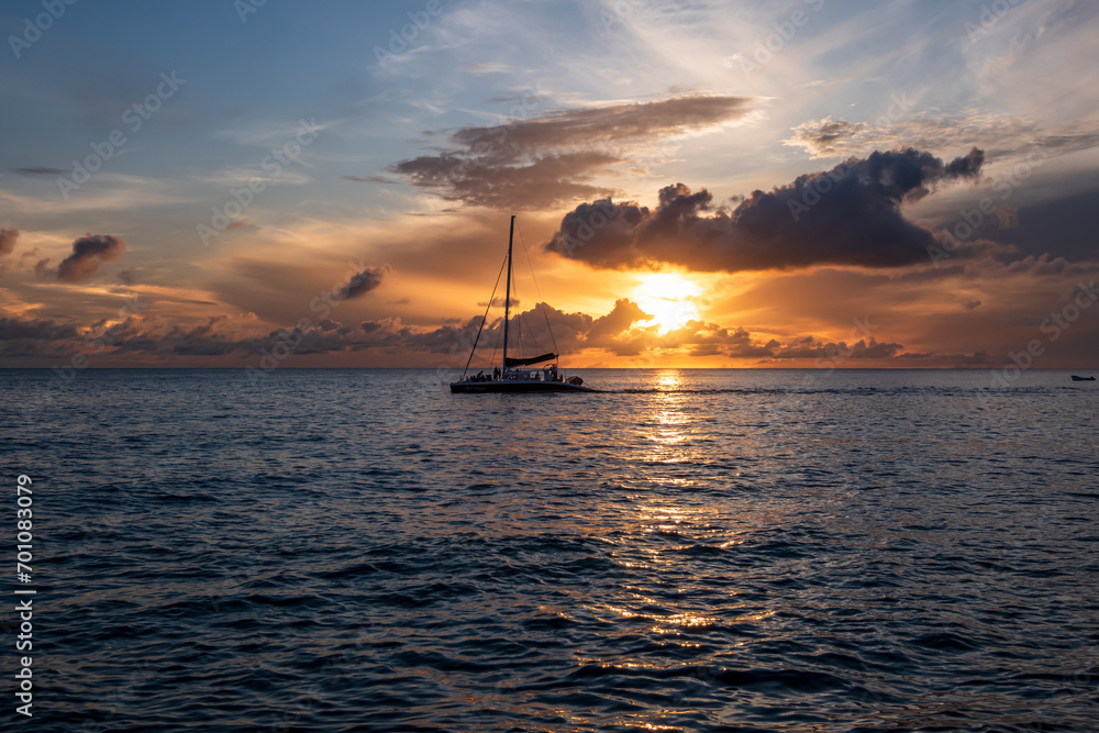 Paynes Bay Beach, Barbados, 08.09.2023: a catamaran sailing during an amazing colorful sunset in the caribbean sea.