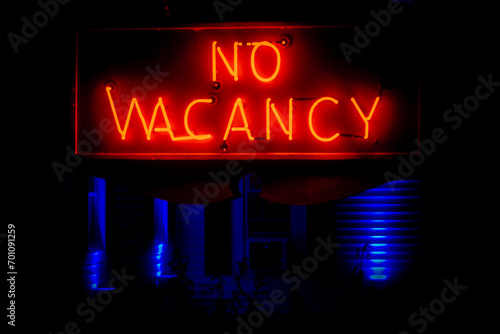 neon no vacancy sign at night in front of motel with blue lights photo