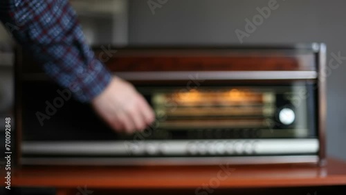 A man turns on a retro radio and searches for a radio wave. Blurred video. photo