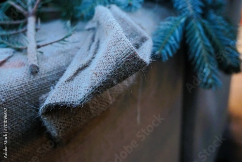 Weihnachtsdekoration mit braunem Jutesack und frischen grünen Tannenzweigen auf brauner Holzkiste  photo
