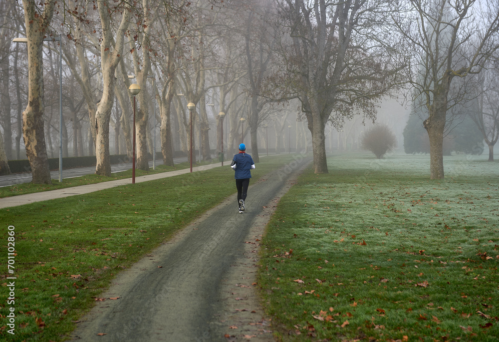 an athlete runs in the park on a foggy winter morning an athlete runs in the park on a foggy winter morning