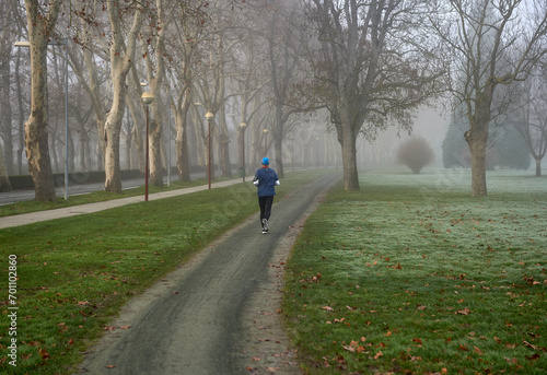 an athlete runs in the park on a foggy winter morning