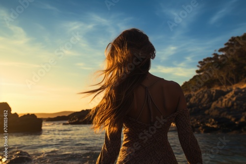 Woman on the beach standing against sunset background