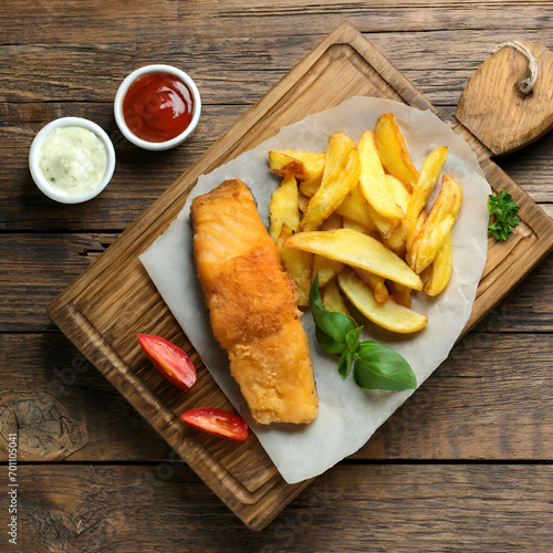 Board with British traditional fish and potato chips on wooden background, top view.