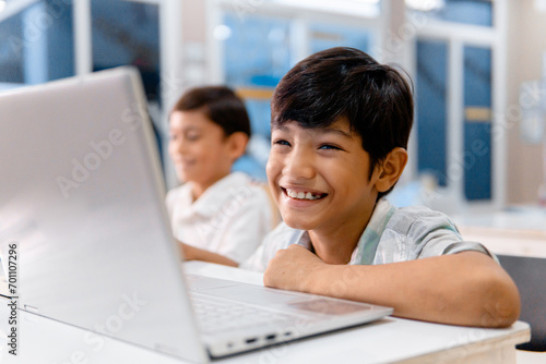 Portrait school cheerful boy using digital device in school classroom.