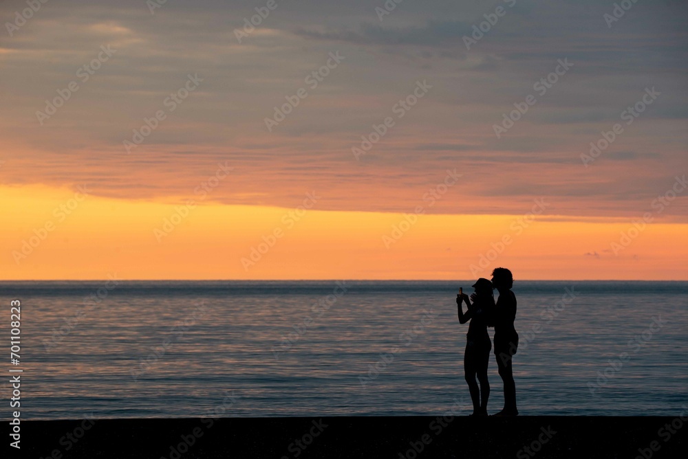 girl with boyfriend taking pictures of sunset on the sea in Batumi