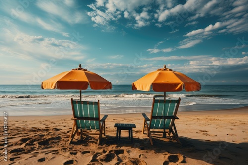 Two sun loungers sit under a large umbrella on the golden sand. Theme of rest and relaxation.