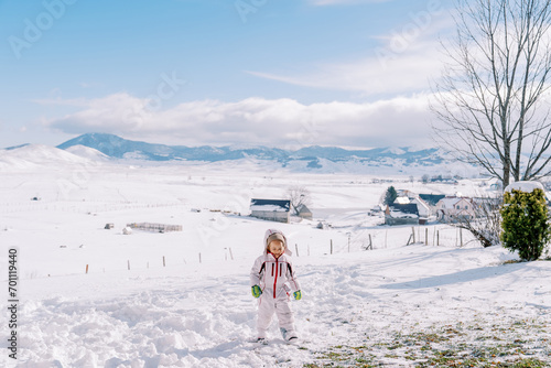 Little girl walks on a snowy plain in the mountains, looking at her feet