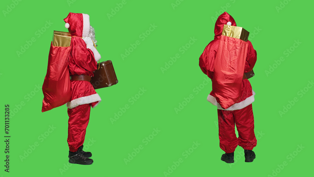 Saint nick with bag of presents and briefcase, looking for transportation to deliver gifts to kids around the globe. Young person portraying santa claus with vintage suitcase and red sack.