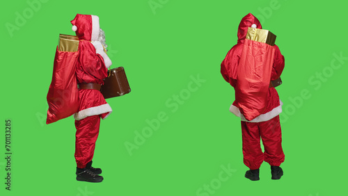 Saint nick with bag of presents and briefcase, looking for transportation to deliver gifts to kids around the globe. Young person portraying santa claus with vintage suitcase and red sack.